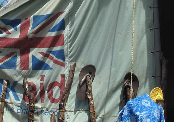 A woman stands in front of a tent supplied by UK aid, Philippines