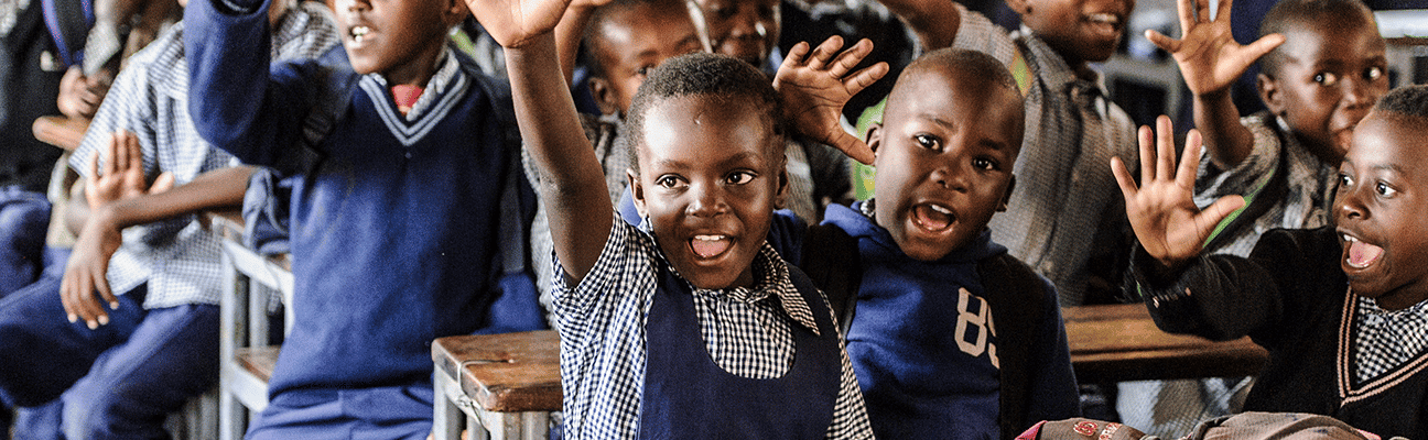 Children in school in Zambia raising their hands