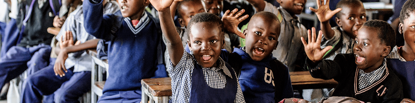 Children in school in Zambia raising their hands