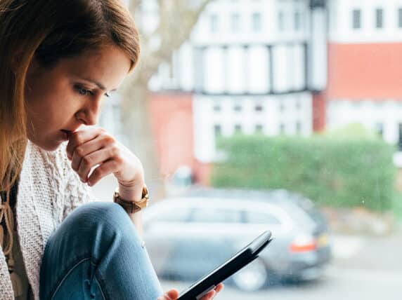 Woman sits with her phone