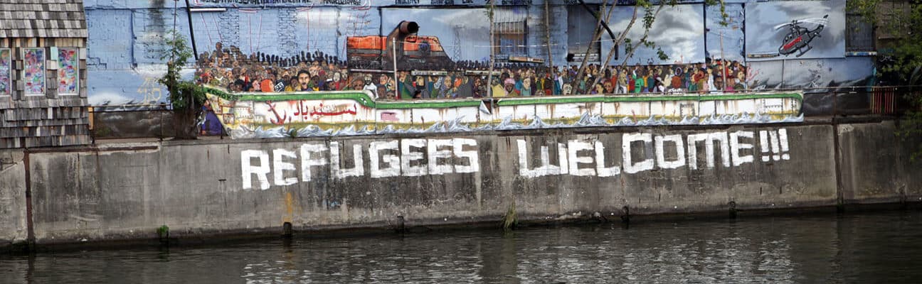Riverside designed as a boat and Refugees Welcome written on wall