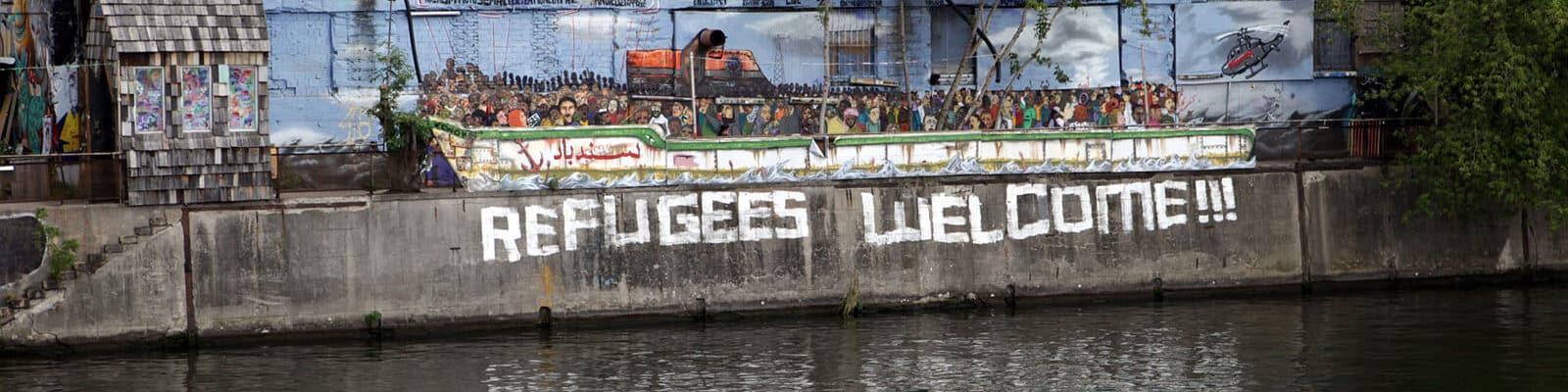 Riverside designed as a boat and Refugees Welcome written on wall