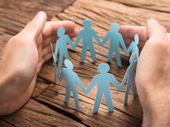 Cropped image of hands covering paper team on wooden table